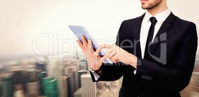 Composite image of mid section of a businessman using digital ta