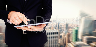 Composite image of mid section of a businessman touching digital