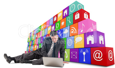 Composite image of mature businessman sitting using laptop