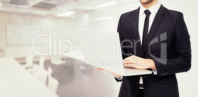 Composite image of mid section of a businessman using laptop