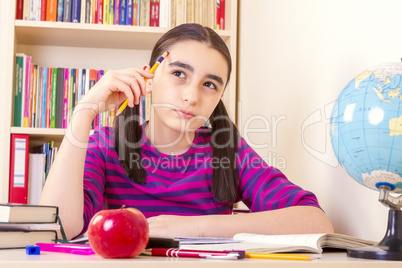 Little schoolgirl holding a pencil and thinking