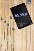 Renew against tablet and plugs on wooden background