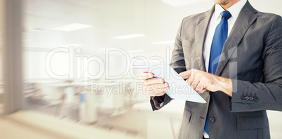 Composite image of businessman using his tablet pc