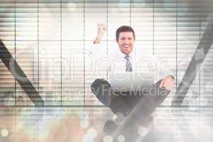 Composite image of businessman using laptop and cheering