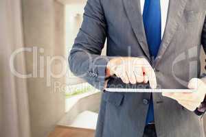 Composite image of businessman using his tablet pc