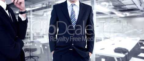 Composite image of smiling businessman standing with hands in po