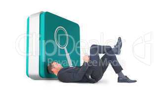 Composite image of businessman lying on the floor reading book