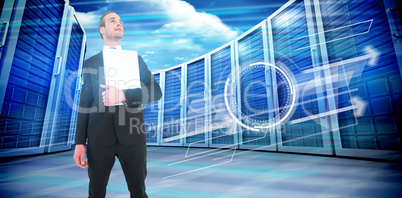 Composite image of businessman looking up holding laptop