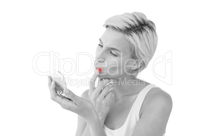 Composite image of beautiful blonde looking her skin in the mirr