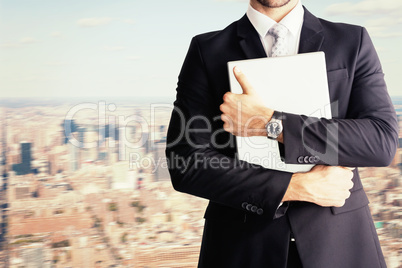 Composite image of mid section of businessman holding computer