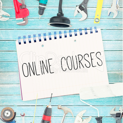 Online courses against tools and notepad on wooden background