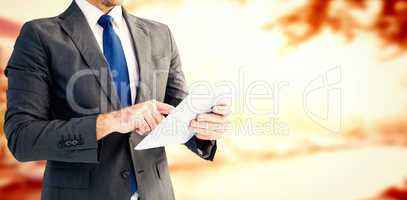 Composite image of businessman using his tablet pc