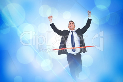 Composite image of happy businessman crossing finishing line