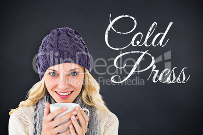 Composite image of pretty blonde in winter fashion holding mug