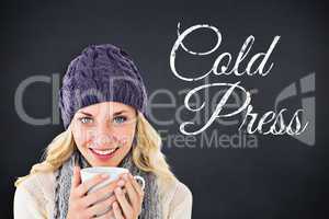 Composite image of pretty blonde in winter fashion holding mug