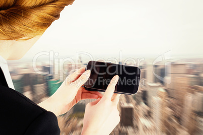 Composite image of businesswoman holding smartphone showing scre