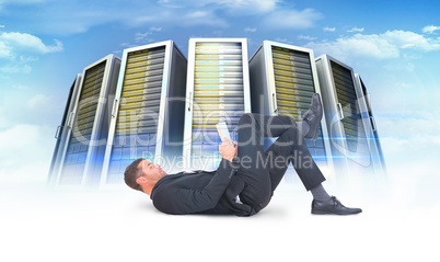 Composite image of businessman lying on the floor reading book