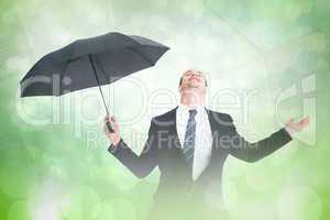 Composite image of businessman sheltering under black umbrella t