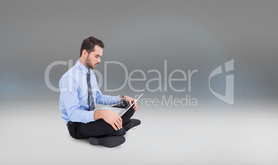 Composite image of cheerful businessman sitting on the floor usi