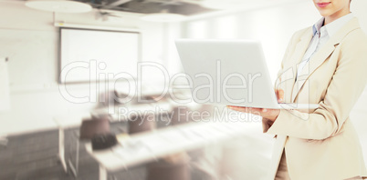 Composite image of confident businesswoman holding laptop