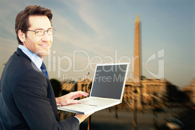 Composite image of smiling businessman using a laptop