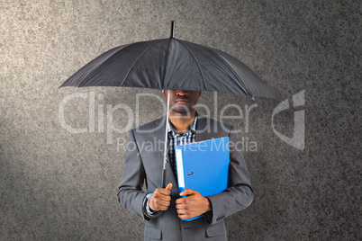 Composite image of businessman standing under umbrella