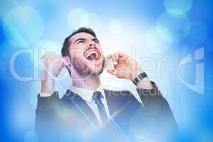Composite image of cheering businessman in suit on the phone