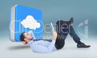 Composite image of businessman lying on floor using tablet