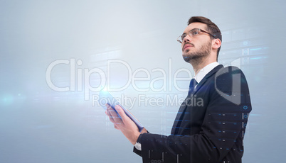 Composite image of businessman looking away while using tablet