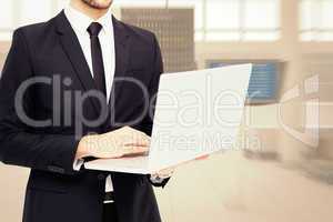Composite image of mid section of a businessman using laptop