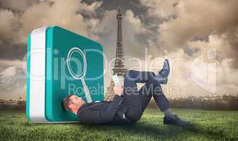 Composite image of businessman lying on the floor reading book