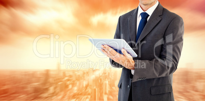 Composite image of serious charismatic businessman holding a tab