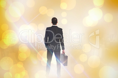 Composite image of rear view of businessman holding a briefcase