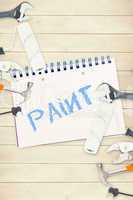 Paint against tools and notepad on wooden background