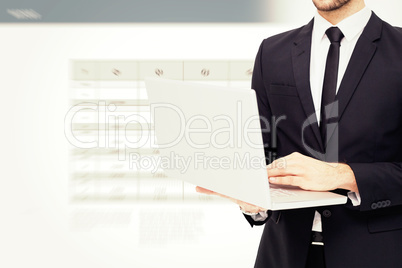 Composite image of mid section of a businessman using laptop