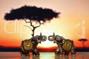 Two miniature elephant at sunset
