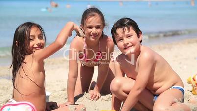 Kids playing on beach and smiling to camera