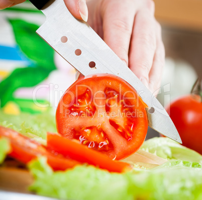 Woman's hands cutting tomato