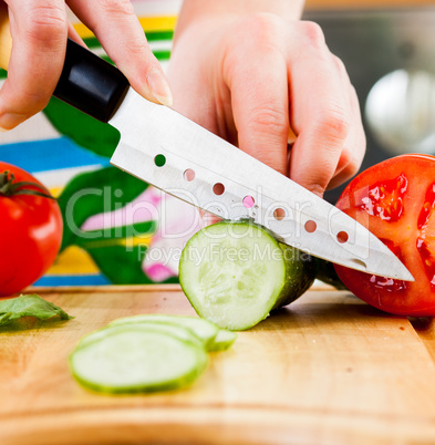 Woman's hands cutting cucumber