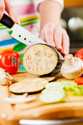 Woman's hands cutting aubergine eggplant