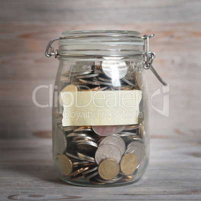 Coins in glass money jar with blank label