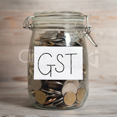 Coins in glass money jar with gst label