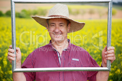 Farmer with photo frame is placed in canola field