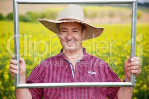 Farmer with photo frame is placed in canola field
