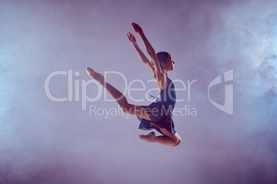 Beautiful young ballet dancer jumping on a lilac background.