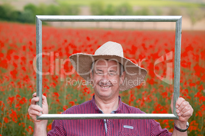 Farmer with photo frame is placed in canola field