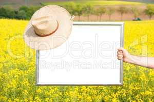 Picture frames with straw hat in rape field