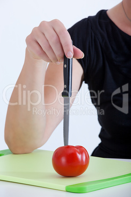 Woman with knife cut the tomato