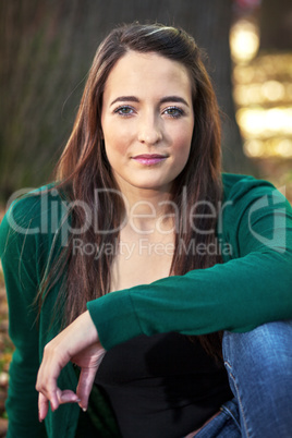 Woman sitting in the autumn before the tree trunk