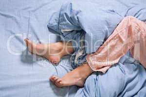 Bare Feet of a Young Woman on Blue Bed